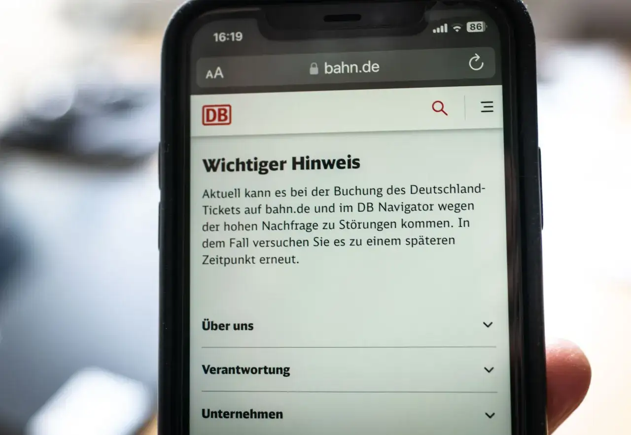 Hand h&auml;lt Smartphone mit Meldung zu St&ouml;rungen bei Buchung des Deutschland-Tickets auf bahn.de.