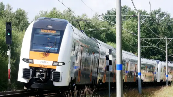 Der Rhein-Express fährt auf einer Sonderfahrt durch eine grüne Landschaft.